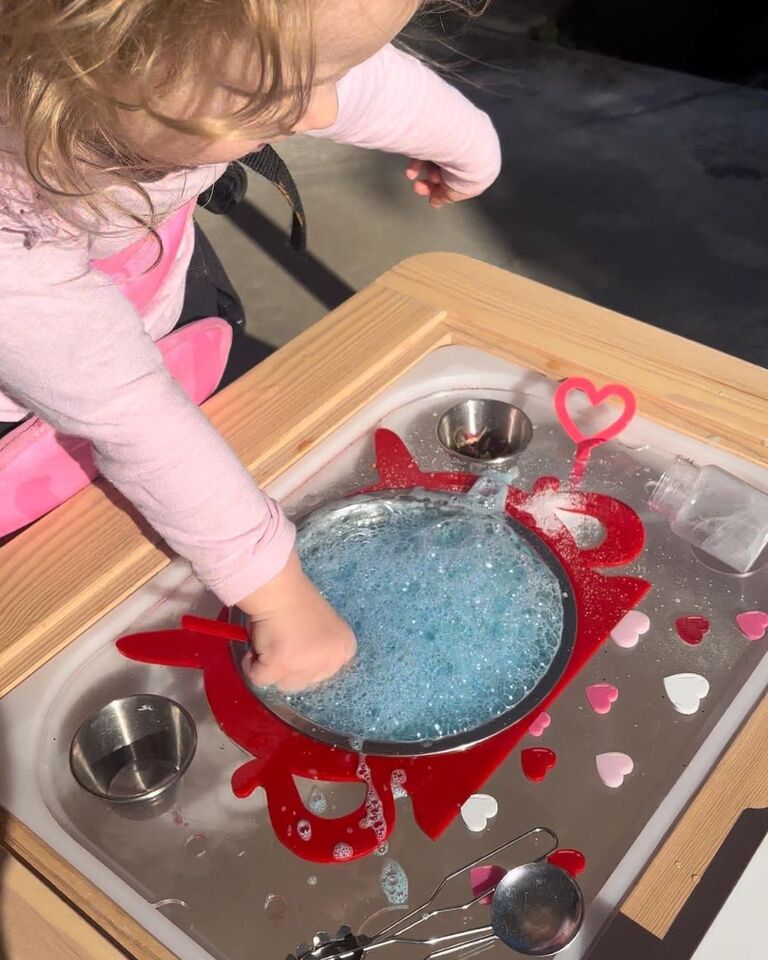 little girl in pink playing with blue bubbly magic potion